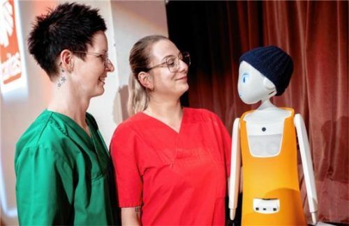 Die Pflegefachkräfte Jaqueline Klee (links) und Annika Meyer sprechen mit dem Pflegeroboter „Navel“. Künstliche Intelligenz und Technik könnten in der Altenpflege eine Rolle spielen. Foto dpa