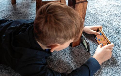 Ein Junge spielt ein Videospiel auf seinem Smartphone und überträgt es mit einem zweiten Handy per Facetime zu seinem Freund. Foto dpa