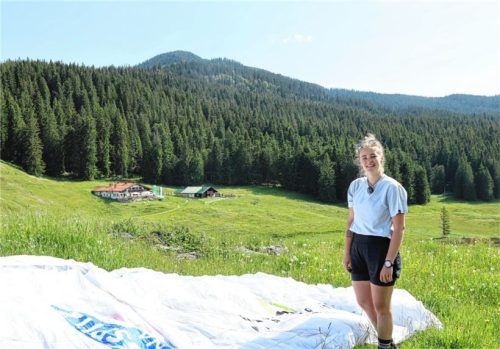 Celine Lorenz zeigt ihren Gleitschirm. Im Hintergrund ist ihr Zuhause, die Traunsteiner Hütte auf der Winklmoos Alm, zu sehen. Die Extremsportlerin will bei einem der härtesten Rennen der Welt nach 1283 Kilometern über die Alpen ins Ziel kommen. Foto Nägele