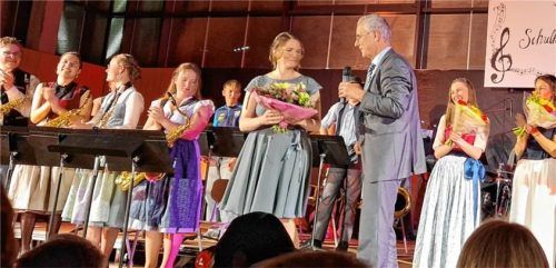Ein bewegender Moment auf der Bühne: Schulleiter Alois Plomer, umringt von seinen musizierenden Schülern, bedankt sich gerührt bei den Lehrkräften und den leitenden Helfern mit einem Blumenstrauß.Foto Steffenhagen
