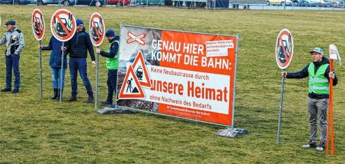 Gegner der geplanten Bahntrasse stehen mit Schildern auf einem Sportplatz, welcher der Strecke weichen müsste. Foto dpa