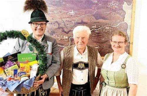 Leonhard Obermaier (Mitte) erhält einen Geschenkkorb aus den Händen von Vorsitzenden Helmut Freund (links) und Irmi Aicher vom GTEV Wildenwart. Foto  Hötzelsperger