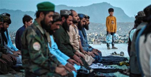 Taliban beten auf dem Nadir-Khan-Hügel in Kabul, während ein Junge sie beobachtet. Foto dpa
