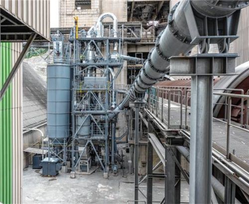 Die Vorderansicht der Anlage: Links im Bild ist das Silo mit dem Rohmaterial zu sehen, in der Mitte die Brennkammer und rechts der Drehrohrofen und die Leitung für die Klinkerkühlerabluft. Foto  Rohrdorfer Unternehmensgruppe