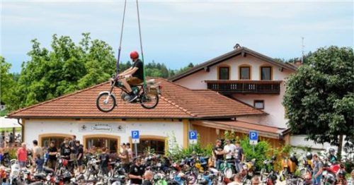 Ein Kran hebt eine Simson samt Fahrer in schwindlige Höhen über die Dächer von Gollenshausen.