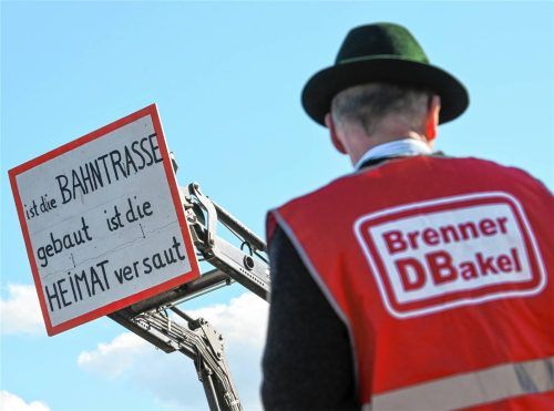Ein Mann trägt bei einer Demonstration gegen den nördlichen Teil des Brenner-Nordzulaufs eine Weste mit der Aufschrift „Brenner DBakel“ während ein Schild mit der Aufschrift „ist die Bahntrasse gebaut ist die Heimat versaut“ zu sehen ist. Foto dpa