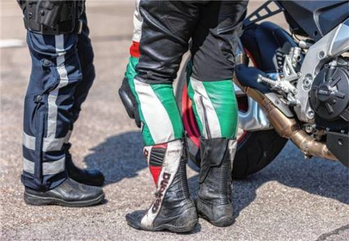 Ein Polizist steht neben einer Motorradfahrerin und ihrem Motorrad. Hunderte solcher Kontrollen wurden jüngst im Alpenraum durchgeführt. Foto dpa (Symbolbild)