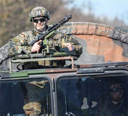 Eine Kolonne mit Fahrzeugen der Bundeswehr und schwer bewaffneten Soldaten fährt über eine Straße. Foto dpa