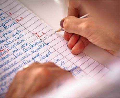Eine Lehrerin korrigiert Hausaufgaben. Foto imago