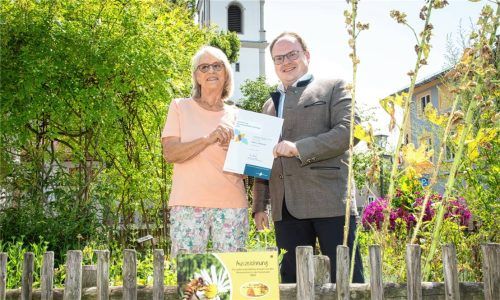 Stolz auf die Auszeichnung: Bürgermeister Andreas Friedrich (rechts) und Umweltreferentin Angela Kind präsentieren im Kräutergarten vor dem Rathaus die Urkunde „Bienenfreundliche Gemeinde“ des Bezirks Oberbayern.Foto  Berger