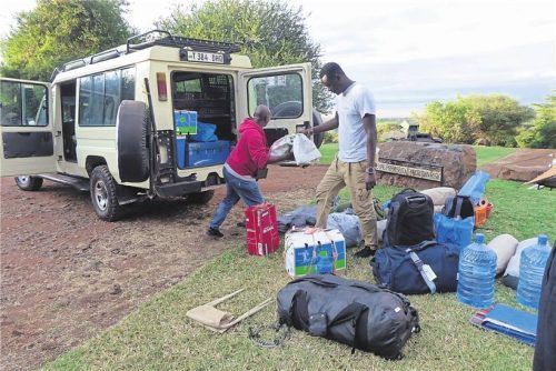 Unterwegs mit einem Massai: Guide Baraka (r.) belädt den Jeep mit Essen und Wasser. Foto AndreaS DROUVE/DPA-TMN