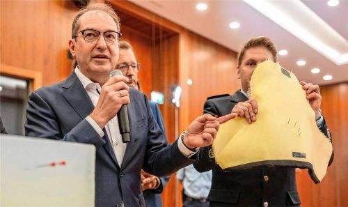 Bundesinnenminister Alexander Dobrindt (links) demonstriert die Durchschlagskraft der neuartigen Druckluftpistole, die jetzt verboten wurde. Die Geschosse der Pistole können sogar Schutzwesten von Sicherheitskräften durchschlagen.