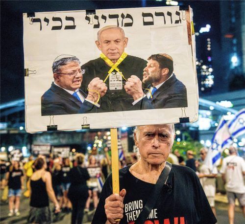 Ein Demonstrant hält ein Plakat, auf dem Bezalel Smotrich und Itamar Ben Gvir zu sehen sind, wie sie Ministerpräsident Netanjahu mit einem gelben Band erwürgen.Foto dpa