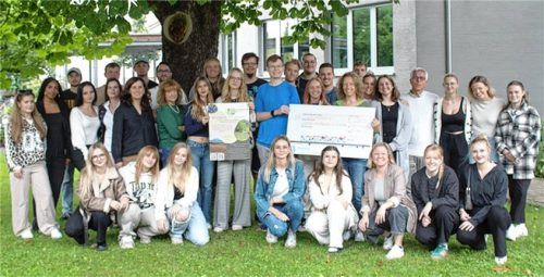 Ein Umweltprojekttag wirkt mit einer weiteren guten Tat nach: Stolz übergeben die Schüler mit Lehrkräften der Romed-Berufsfachschule für Pflege in Rosenheim einen Spendenscheck an Monika Maier vom Landschaftspflegeverband Rosenheim (stehend, Achte von rechts). Foto RoMed-Kliniken