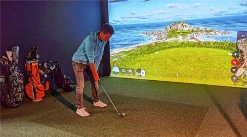 Dominik Haas hält den Schläger zum Golfball. Gleich wird er ausholen und den Ball in die Leinwand schlagen. Foto Weinfurtner