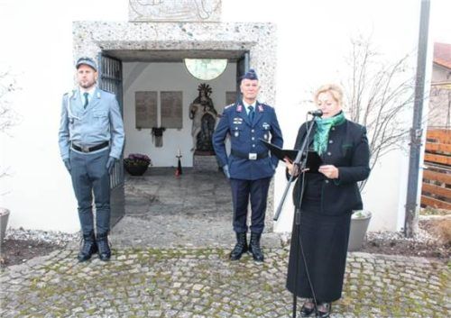 Bürgermeisterin Susanne Grandauer legt am Ehrenmal der Gemeinde Nußdorf am Inn einen Kranz nieder, während die Ehrenwache des Krieger-, Veteranen- und Kameradschaftsvereins Nußdorf e. V. im Hintergrund Stellung bezieht.