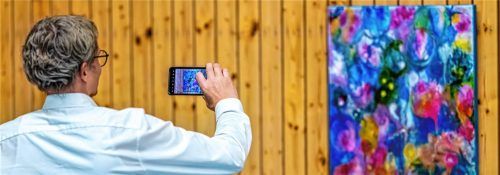 Ein Besucher hebt sein Handy und hält fest, was ihn berührt – ein farbintensives Gemälde, ein Moment von Licht und Bewegung. Kunst begegnet hier dem Alltag: analog und digital, still und zugleich geteilt. Der Wunsch, Schönheit zu bewahren, wird selbst zu einem kleinen Kunstakt. Fotos Nitzsche