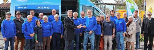 Inmitten der ehrenamtlichen Fahrerinnen und Fahrer übergab Landrat Otto Lederer (Bildmitte) den Fahrzeugschlüssel für den neuen Bus an den ehrenamtlichen Koordinator Norbert Gradmann. Pfarrer Amit Sinha Roy (rechts) segnete nicht nur den Bus, sondern auch alle Fahrerinnen und Fahrer. Foto Landratsamt Rosenheim