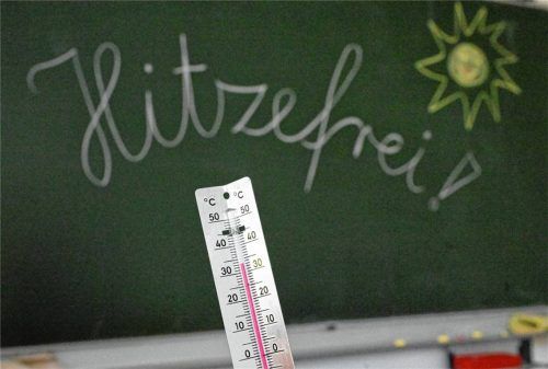 33 Grad werden auf einem Thermometer in einem Klassenzimmer einer Grundschule angezeigt. Auf einer Tafel im Hintergrund hat eine Lehrerin das Wort „Hitzefrei“ geschrieben (Symbolbild). Foto dpa