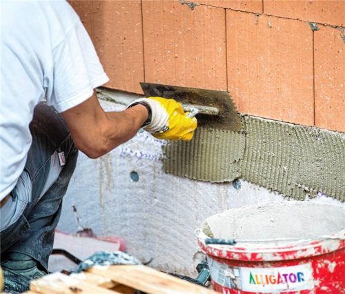 Ein Maurer trägt Klebemörtel an einer Wand auf. Foto dpa