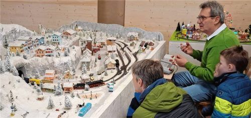 Faszination bei Groß und Klein vor der winterlichen Bahnanlage in H0, die ihr Besitzer, Schreinermeister und Modellbahnfreund Peter Moser (rechts), präsentiert. Foto Steffenhagen