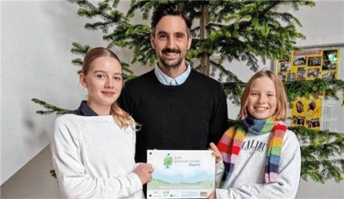 Stolz präsentiert Lehrer Bernhard Rautz gemeinsam mit zwei Schülerinnen die Auszeichnung für Gesundheitsförderung.

Foto Gymnasium Schloss Ising