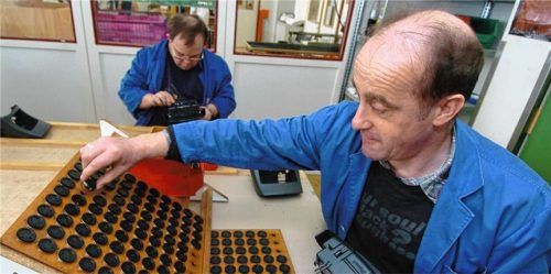 Zwei Männer arbeiten in einer Behindertenwerkstatt an Bauteilen für eine Mittelkonsole in einem Fahrzeug. Foto dpa