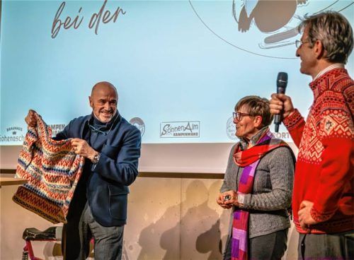 Christian Neureuther zeigte beim Eröffnungsabend der „Aschauer Skiroas 2026“ einen gestrickten Rennpullover. Diesen trug Rosi Mittermaier 1967 bei den deutschen Meisterschaften an der Kampenwand. Auch Evi Mittermaier, die jüngere Schwester von Rosi Mittermaier, und Co-Moderator Georg Antretter (rechts) vom Heimat- und Geschichtsverein Aschau erinnerten an die Wettkampfzeiten an der Kampenwand.