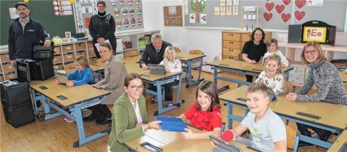 Erstkontakt mit dem neuen Material: Thomas Hiemer von der Firma Agelero und das „I-Pad-Empfangskomitee“ (von links) Rathaus-IT-Spezialistin Cornelia Schweiger (stehend), Alexandra Zinner und Katrin August von Pro Design (sitzend), Bürgermeister Richard Richter, Rektorin Renate Bruckmeier, Dritte Bürgermeisterin und Schulreferentin Anna Wallner sowie sechs Schulkinder. Foto baumann