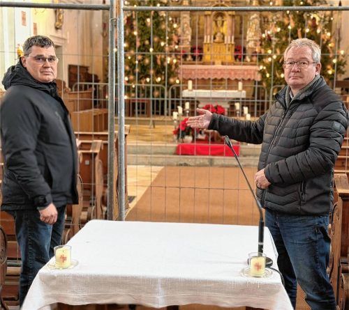 Kirchenpfleger Holger Dietl (links) und Verwaltungsleiter Michael Liegl vor dem Bauzaun, der den Altarraum derzeit vom Kirchenschiff trennt. Foto Kotter