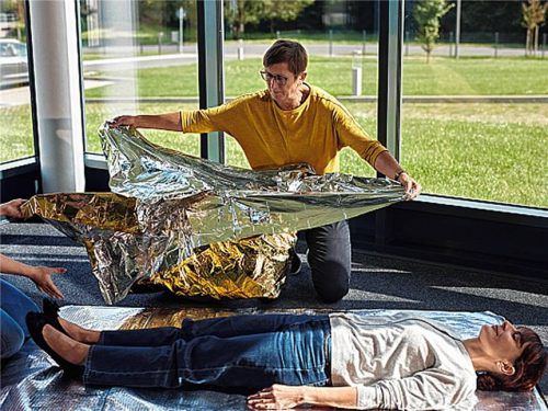 Eine Erste-Hilfe-Ausbilderin der Johanniter unterstützt eine Kursteilnehmerin dabei, in einer Simulation eine Verletzte mit einer Rettungsdecke zu versorgen. Foto Johanniter-Unfall-Hilfe