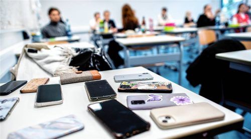 Zahlreiche Smartphones der Schüler werden auf einem Tisch im Klassenzimmer gesammelt. Foto dpa