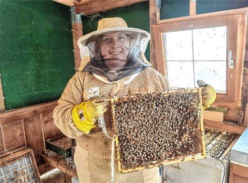 Christina Follner aus Heldenstein hält einen Rahmen voller Bienen hoch. Foto Weinfurtner