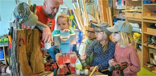 Ein Erzieher bastelt in der Kinderwerkstatt einen Roboter mit mehreren Kindern. Foto dpa