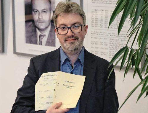 Geschichtskoordinator Daniel Baumgartner mit der Wahlordnung und dem Wahlzettel zur ersten Kreistagswahl nach dem Ende der NS-Diktatur. Das Foto im Hintergrund zeigt Sebastian Goßner, der 1946 von den Mitgliedern des Kreistags zum Landrat gewählt wurde. Foto  Landratsamt