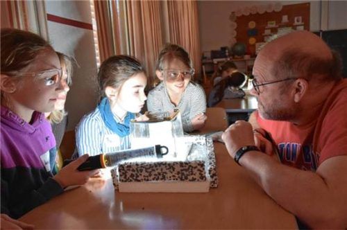 Schülerinnen und Physiker Dr. Ralf Averbeck beim Beobachten der Teilchen in der Nebelkammer. Foto Wunderlich
