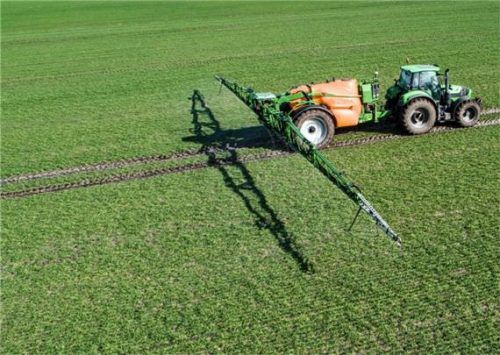 Traktor mit Pflanzenschutzspritze im Feld-Einsatz. Foto Adobe Stock