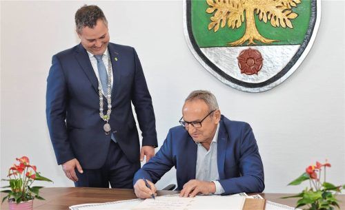 Unter den Augen von Bürgermeister Christian Weyrich (links) trägt sich Altbürgermeister Alois Salzeder in das Ehrenbuch der Gemeinde Aschau ein. Foto höpfinger