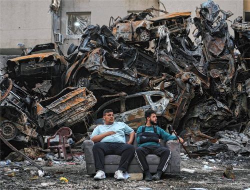 Anwohner sitzen auf einem Sofa vor verkohlten Autos am Standort eines Gebäudes, das bei einem israelischen Luftangriff im Zentrum von Beirut zerstört wurde. Foto dpa