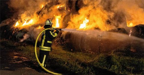 Ein Feuerwehrmann löscht brennende Strohballen (Symbolbild). Foto dpa