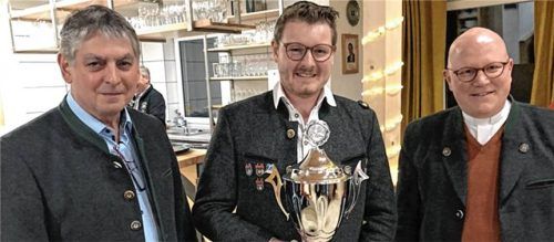 Georg Müller (links), 1. Schützenmeister der SG Haigerloh und Pfarrer Florian Regner (rechts) überreichten Schützenmeister Julian Schick den Siegerpoka.lFoto re