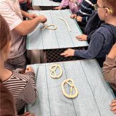 Kleine Hände drehen Brezen