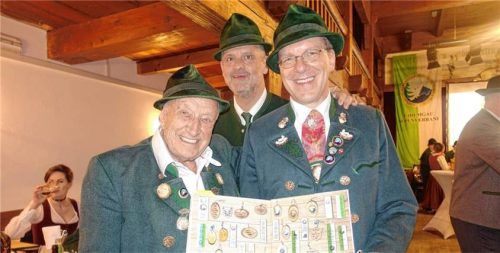 Ehrenmitglied Erich Hagner (von links), Standartenträger Christian Härtl und Gauvorsitzender Thomas Heindl präsentieren die Chronik des Chiemgau-Alpenverbandes. Foto Hötzelsperger
