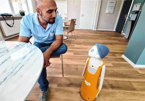 Ergotherapeut Tobias Fröhling unterhält sich mit Iwa, dem humanoiden Roboter im Innovationszentrum. Foto Röhrl