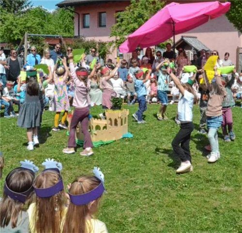 Verkleidete Kinder führen beim Maifest des katholischen Kindergartens St. Irmingard eine Darbietung im Garten auf, während Eltern und Gäste zusehen. Foto re