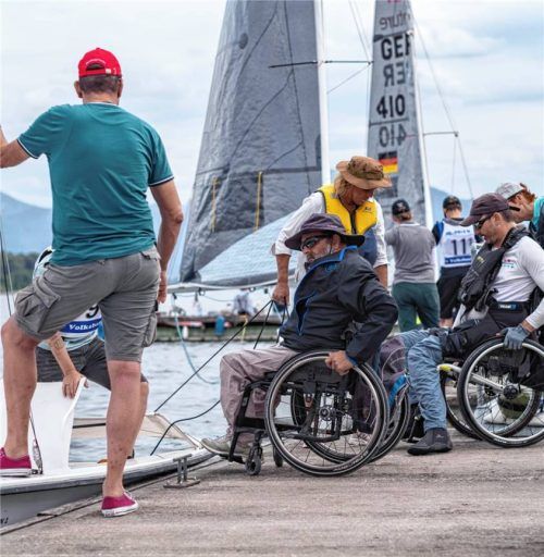 Helfer unterstützen Rollstuhlfahrer beim Wechsel in die Regattaboote während der inklusiven Segelmeisterschaft am Chiemsee. Foto Dagmar Pasch