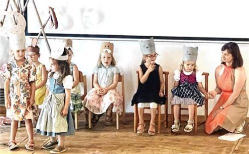 Kinder führen auf der Bühne ein Stück mit Tierhüten auf und werden von einer Erzieherin begleitet.