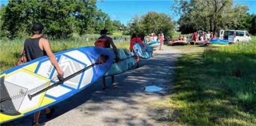 Wasserfreunde tragen in Seebruck ihre Stand-Up-Paddle-Boards und Boote in Richtung Einstiegsstelle. Foto Gemeinde Seeon-Seebruck