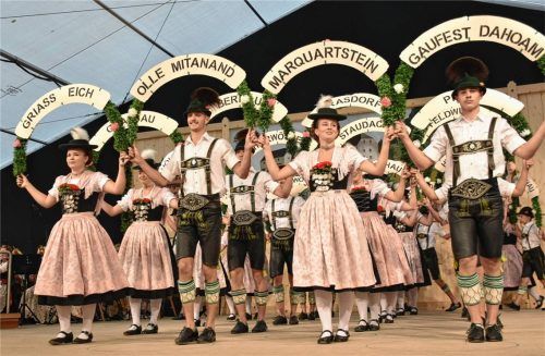 Aktive Tänzer präsentieren den Jubiläumstanz mit den kunstvoll geschmückten Ortsschildern. Fotos Wunderlich