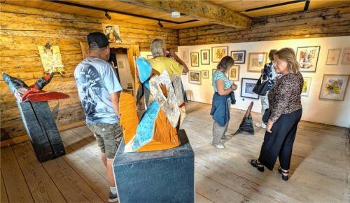 Besucher betrachten die Kunstwerke von Josef Huber im Industriemuseum „Blaahaus“, darunter markante Skulpturen im Vordergrund und gerahmte Bilder an den Holzwänden. Foto  Hoffmann